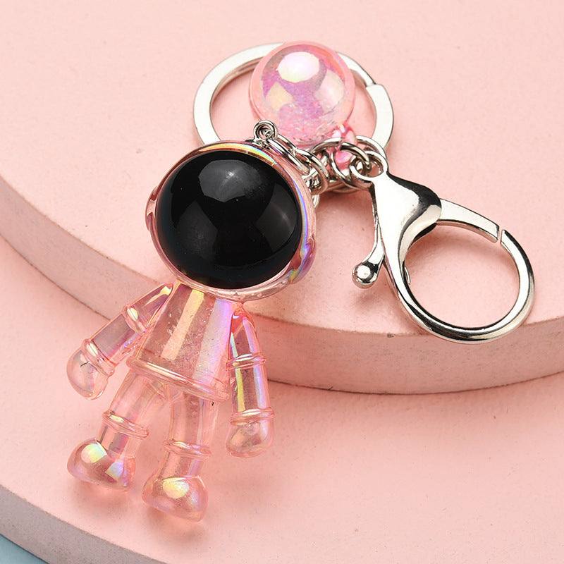 a clear pink and shiny acrylic keychain in the shape of an astronaut