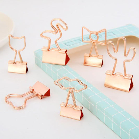 Six gold binder clips of different shapes