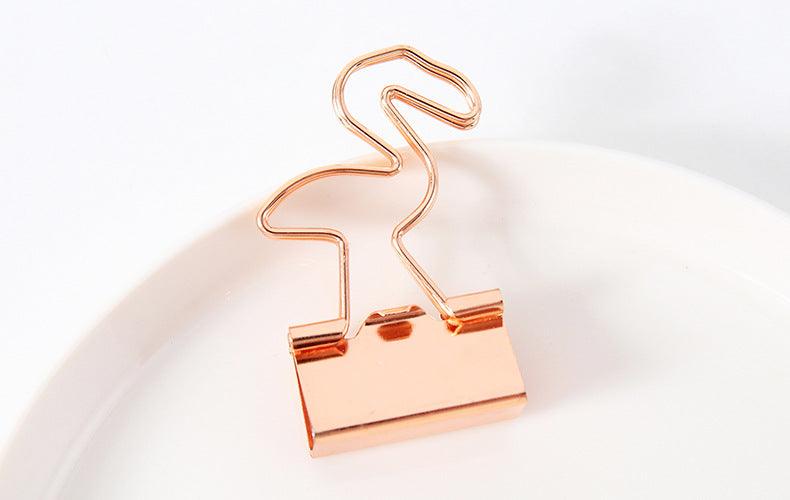 a gold binder clip in a flamingo shape