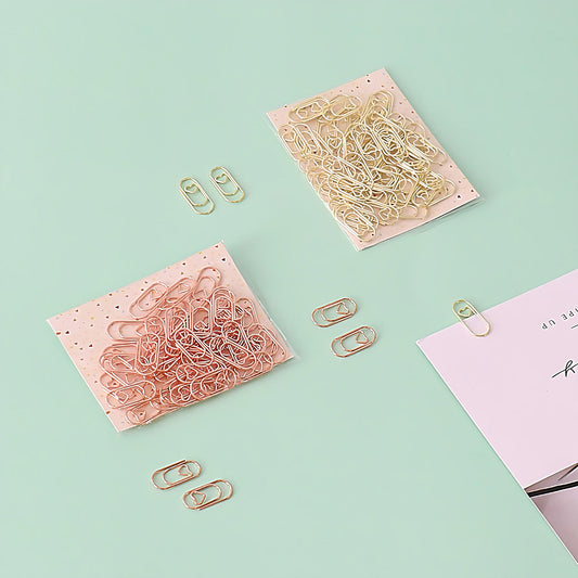 two sets of mini paper clips on a green background