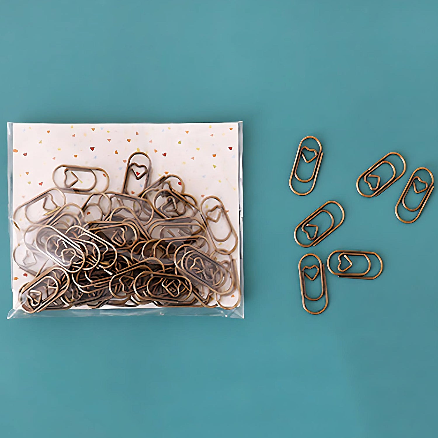 five mini paper clips beside a pack of brass color paper clips