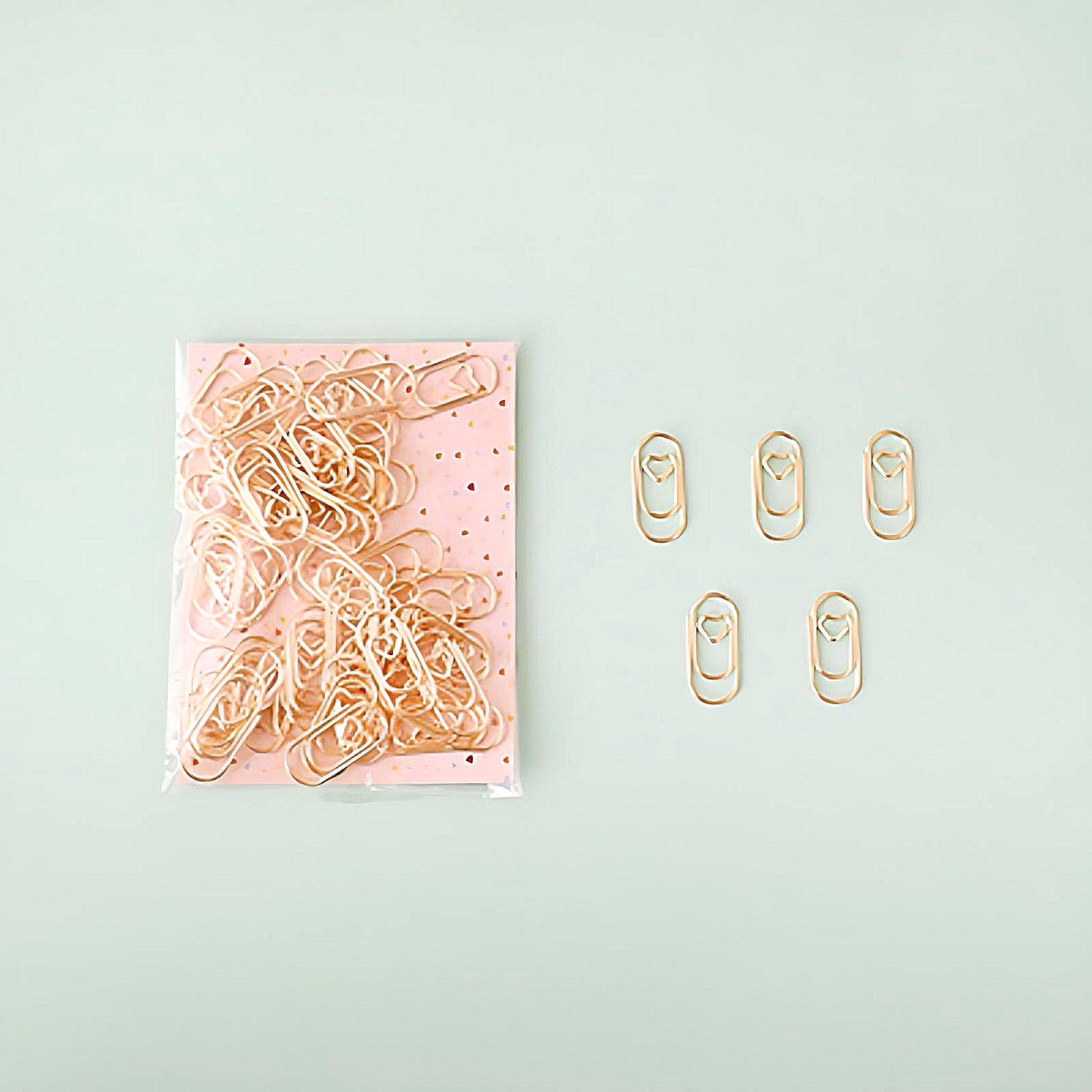 five mini paper clips beside a pack of gold paper clips