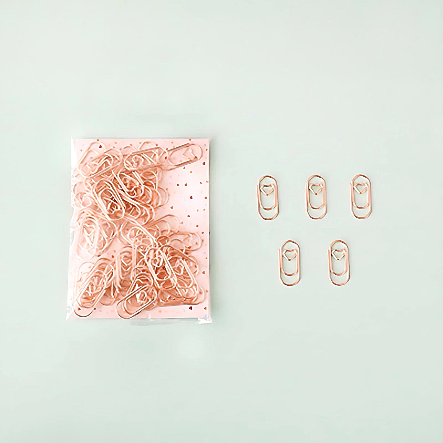 five mini paper clips beside a pack of rose gold paper clips