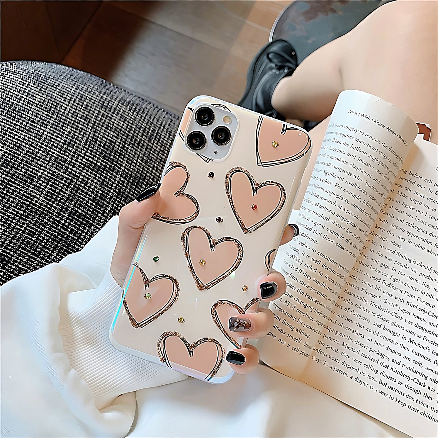 a women holding a silicone phone case with pink heart designs with a book
