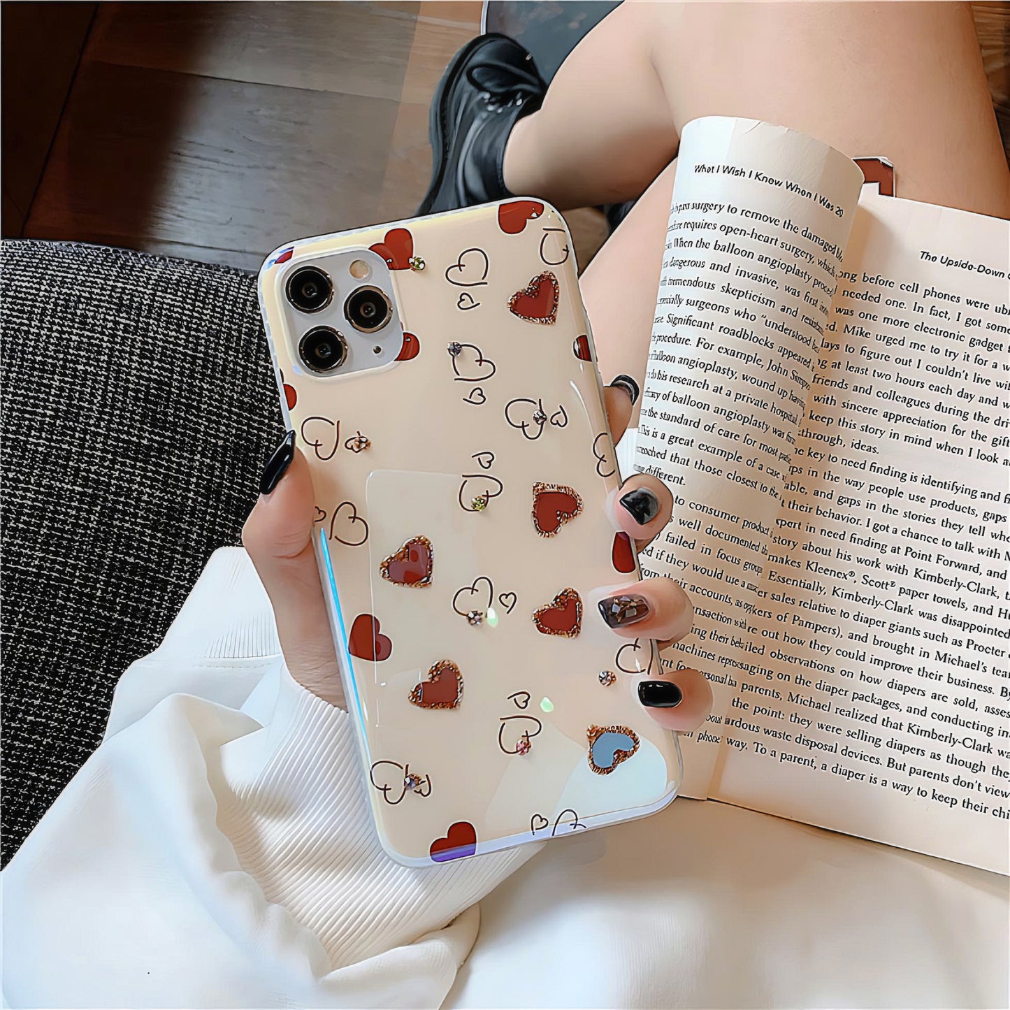 a women holding a silicone phone case with red heart designs with a book