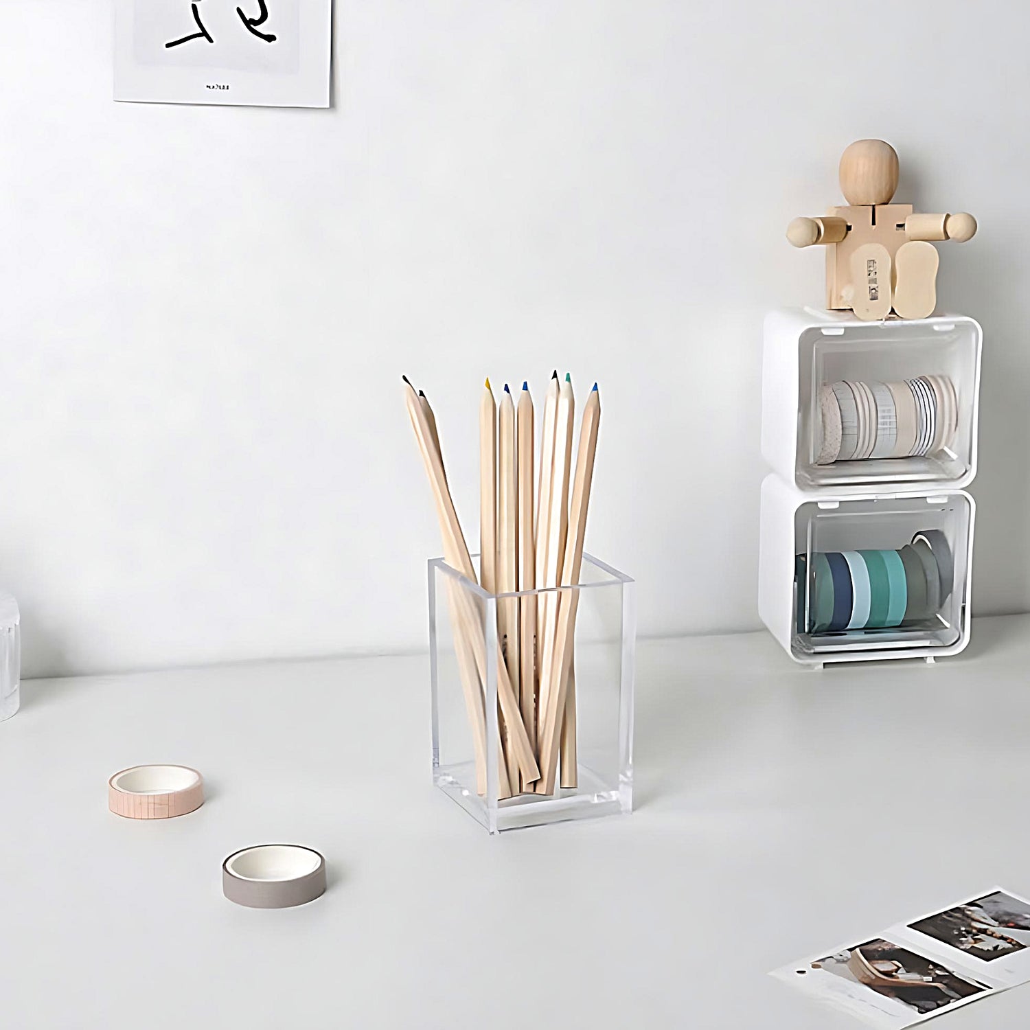a bunch of pencils in a transparent pen holder, on a grey desk beside some washi tapes